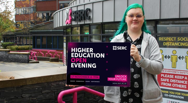 Lea Nickell Outside SERC's Bangor Campus with a board displaying the HE open evening graphic